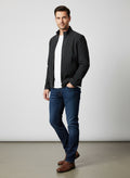 Man wearing stylish black zip-up jacket, white tee, and dark blue jeans for casual fashion look