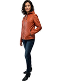 Woman in stylish rust leather hooded jacket with zipper, paired with jeans and boots