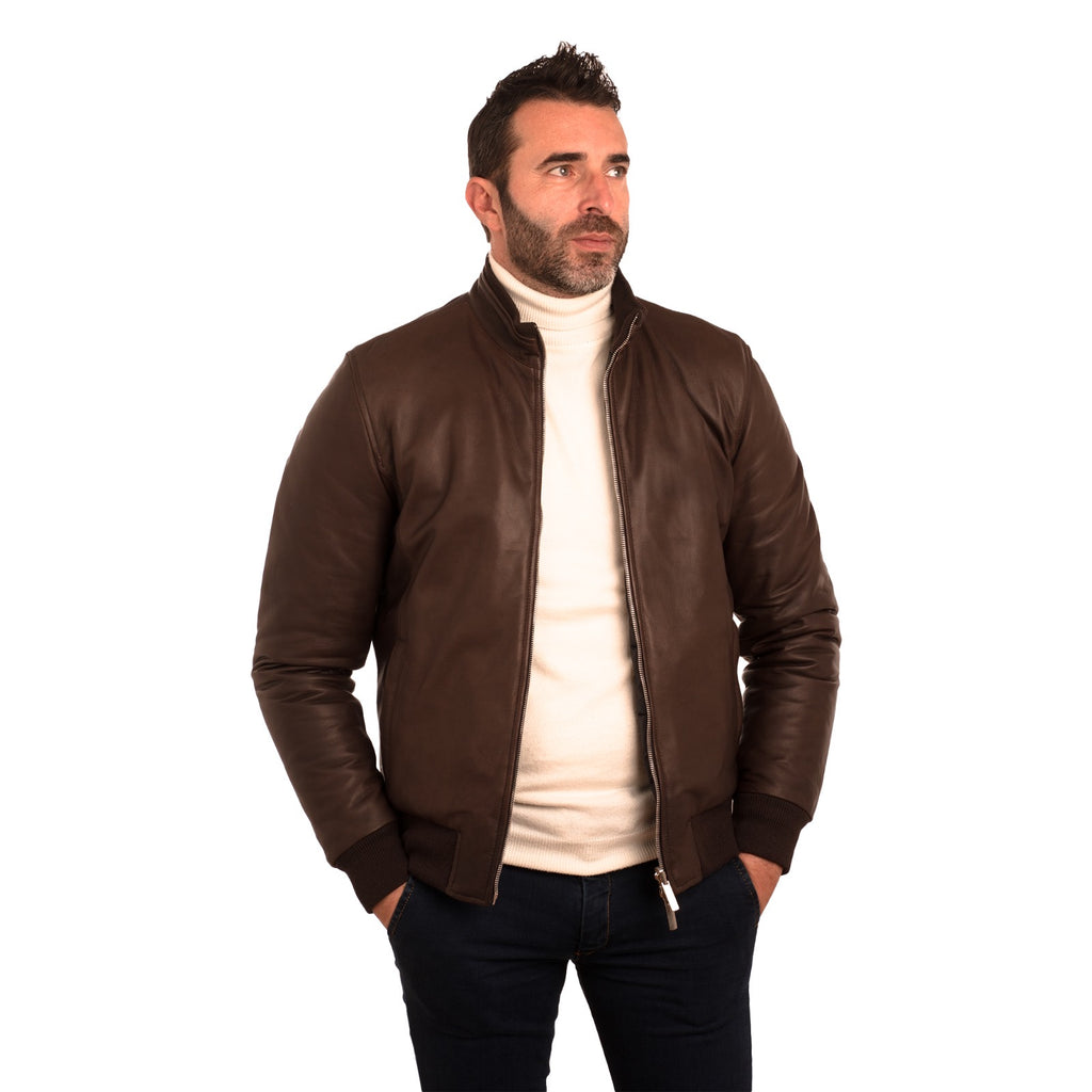 Men's brown leather bomber jacket with ribbed cuffs, styled over cream turtleneck for modern casual wear