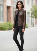 Woman wearing stylish brown leather jacket with black top and jeans, urban street setting