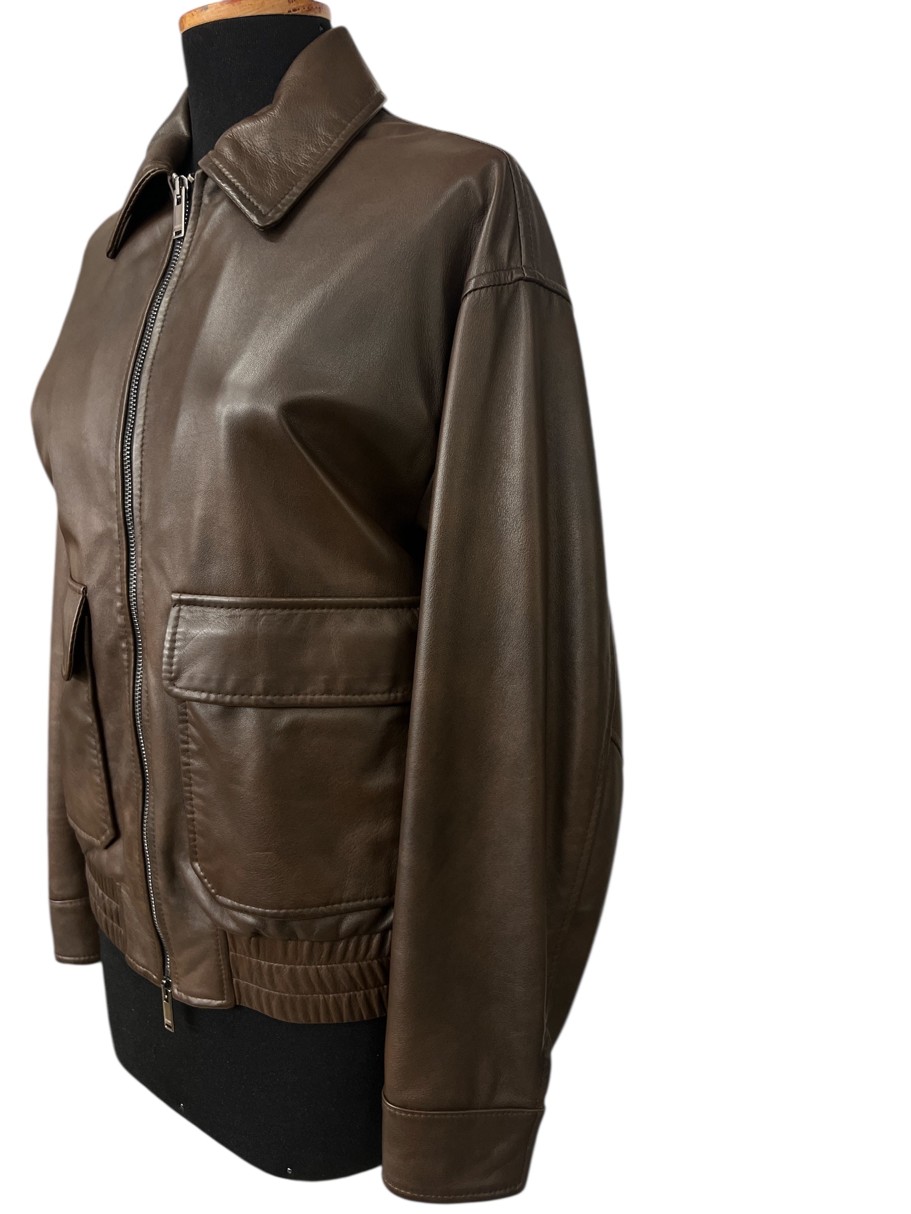 Brown leather jacket with front zipper and pockets, displayed on mannequin for stylish fashion wear