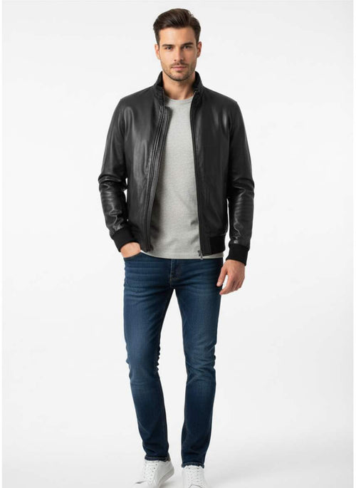 Man wearing a black leather jacket, gray shirt, and blue jeans on a white background