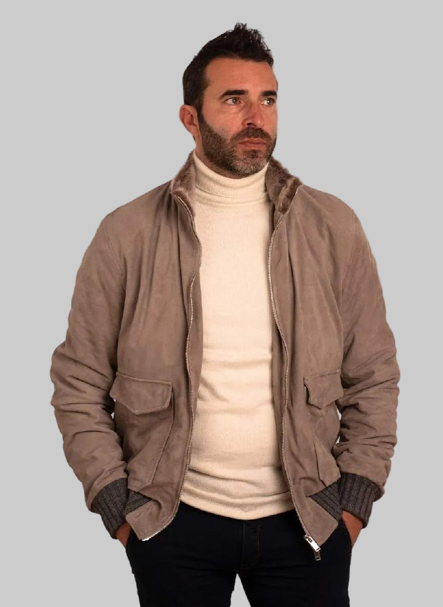 Man wearing a beige jacket over a white turtleneck on a white background